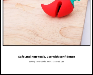 Detail showing the red silicone chili-shaped pot lid lifter on a wooden board