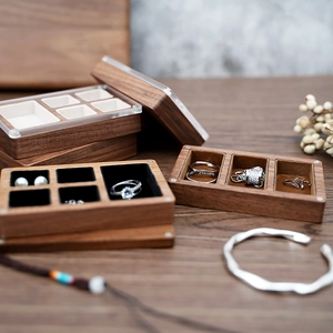 Detail of walnut jewelry box with acrylic lid showing multi-slot ring storage compartments