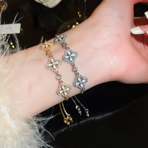 Nahaufnahme verstellbarer Kleeblatt-Armbänder mit Perlmutt und Kristallpavé am Handgelenk