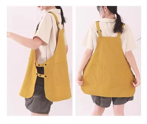 Detail view of the yellow water-repellent apron with side buttons and front pockets