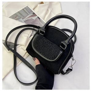 Detail of black mini plush handbag with teddy fleece texture and silver metal hardware