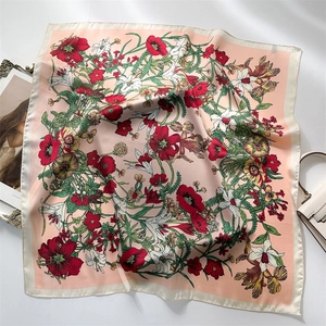 Flat lay of a floral print silk scarf with red blossoms on a pink background