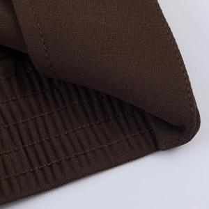 Détail macro du tissu tricoté marron foncé montrant la taille élastique et la texture