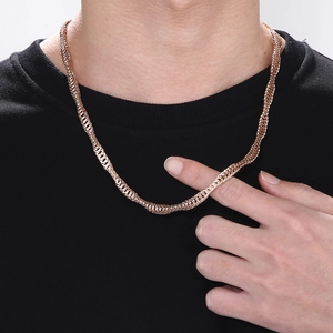 Detailed close-up of a rose gold snake bone chain necklace with woven texture on a model