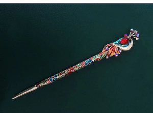 Detailed view of peacock hair stick with red gemstones and floral enamel painting