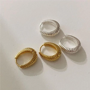 Close-up of gold and silver croissant hoop earrings with elegant spiral texture
