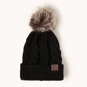 Close-up of black cable knit beanie featuring a faux fur pom-pom and brown leather patch
