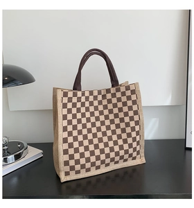 Detail of coffee brown checkerboard linen tote bag with sturdy handles on a desk