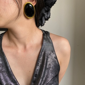 Macro shot of vintage oval black resin earrings with a thick gold metallic frame