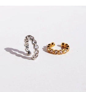 Close-up of gold and silver ear bone clips with sparkling micro-inlaid zircons