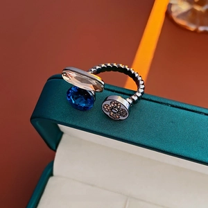 Détail macro d'une bague torsadée argentée avec pierre bleue et pendentif trèfle