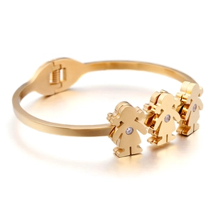 Gold open bracelet with three little girl figures and white zircon inlays on white background