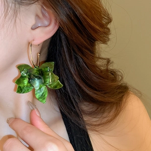 Macro shot of green resin flower petals and gold metal hoop earrings on model