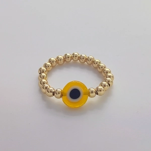 Detail of handmade 18K gold plated beaded ring with a yellow evil eye pendant charm