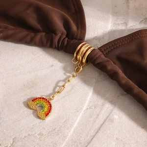 Macro detail of a bikini connector with a gold ring and multi-colored rainbow charm