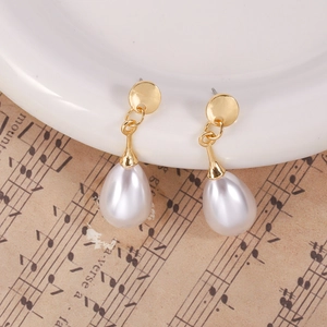 Elegant gold baroque water drop earrings with pearls displayed on a white ceramic plate