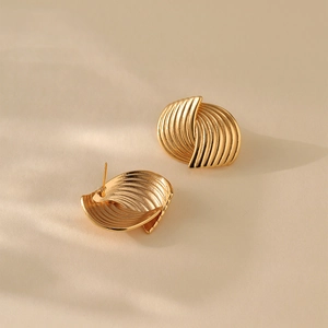 Minimalist irregular textured gold stud earrings with elegant shell-like swirl design