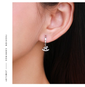 Close-up of S925 silver rocking horse earrings with sparkling zircons on female model