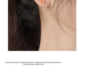 Close-up of small orange floral stud earrings featuring enamel petals and gold center