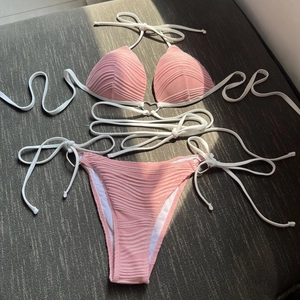 Detailed flat lay of pink ribbed bikini set featuring decorative metal rings and straps