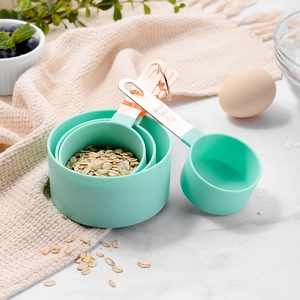 Mint green and rose gold measuring cup set with stainless steel handles on marble surface