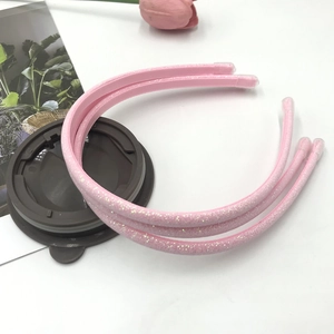 Detailed close-up of pink glitter headbands with protective caps on a minimalist desk