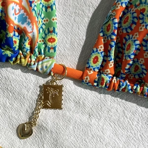 Close-up of paisley bikini with orange ties and palm tree gold pendant charms