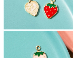Close-up of strawberry enamel charms in red and pink with golden textured backs