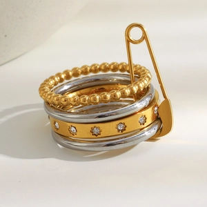 Detailed view of layered stainless steel rings with zircons and creative gold safety pin design