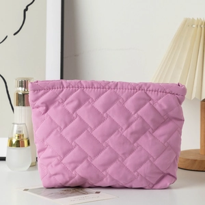 Close-up of pink quilted fabric makeup bag with diamond texture and fine stitching