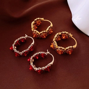 Vue détaillée de boucles d'oreilles en U plaquées or avec roses rouges, oranges et cristaux