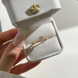 Detailed close-up of a pear-cut pink zircon ring on a golden band in a luxury box