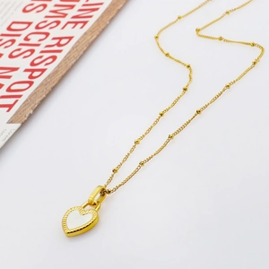 Detail view of 18K gold plated heart pendant with textured edges on a fine bead chain
