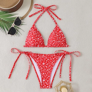 Close-up of red floral bikini set with halter top and side-tie bottoms on beach props