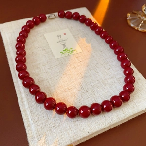 Macro view of smooth deep red glass bead necklace with a glossy metallic clasp