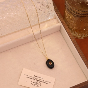 Detail of vintage gold necklace with black oval pendant and red stone in beige jewelry box
