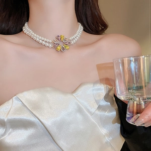 Detail einer zweilagigen Perlenkette mit lila-gelbem Kristallblumen-Anhänger