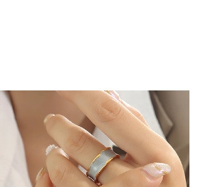 Close-up of minimalist grey enamel ring with gold trim worn on a finger
