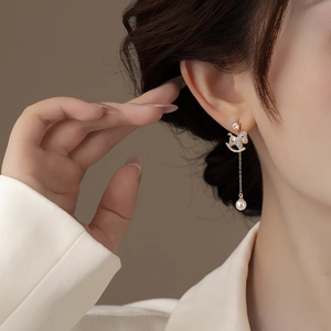 Close-up of gold-plated trojan horse earring with zircon and pearl on model's ear