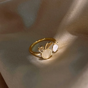 Vue macro d'une bague lapin plaquée or avec pierre œil de chat blanc sur de la soie