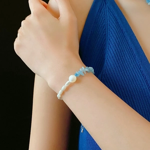 Close-up of a pearl and blue crystal beaded bracelet worn on a female wrist