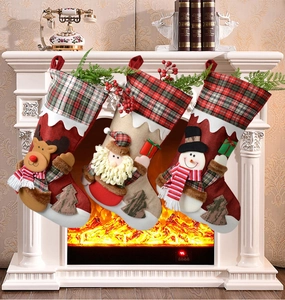Three festive Christmas stockings with elk, Santa, and snowman hanging on a fireplace
