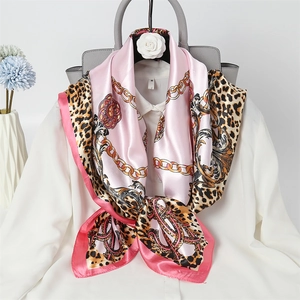 Detail of pink silk scarf with leopard print and golden chain pattern on white shirt