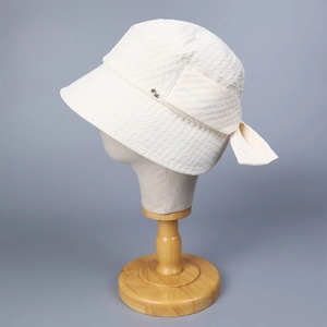 Detailed close-up of white sun hat featuring bow ornament and wavy embossed fabric texture