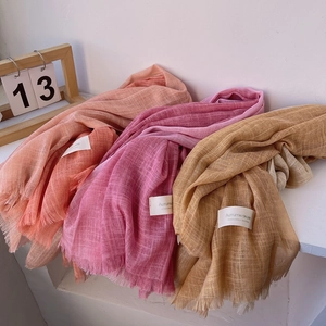 Detailed close-up of cotton linen scarves in orange, pink, and yellow with fringe edges