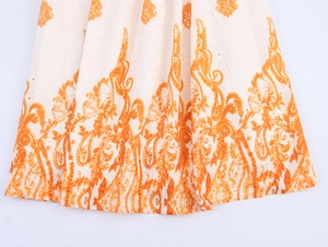 Detalle del estampado floral bohemio y bordado de ojales blancos en vestido de algodón