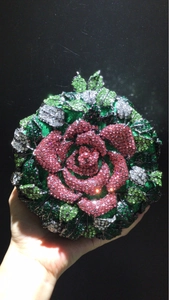 Gros plan d'une pochette de soirée en forme de rose avec cristaux roses et verts