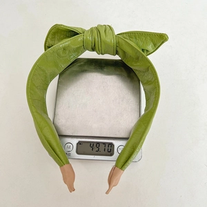 Digital scale showing a 49.70g weight for this green faux leather bow headband