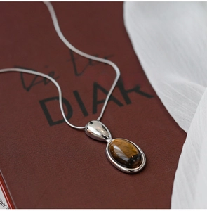 Detailed view of an oval tiger eye stone pendant set in silver on a snake chain