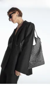 Detail shot of black rhinestone tote bag styled with a professional black tailored blazer
